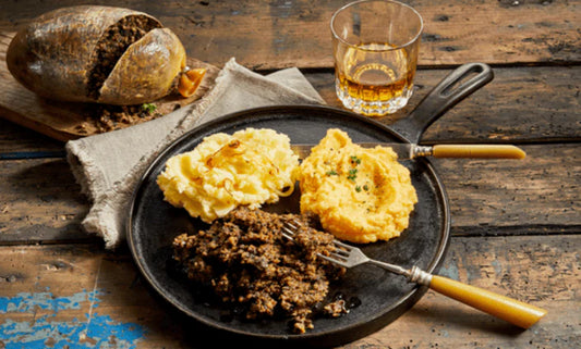 Traditional Burns Supper with Macsween Haggis, neeps, and tatties served on a wooden table.