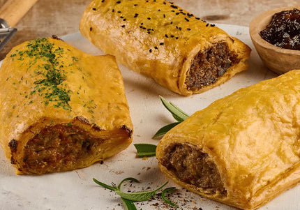 Traditional Scottish Scotch pies and sausage rolls on wooden board