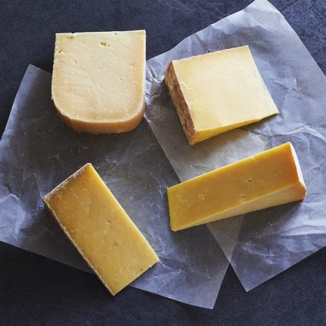 Block of mature Scottish cheddar cheese on wooden board with cheese knife