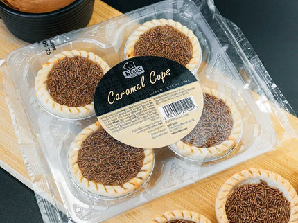 Packaged caramel cupcakes on a wooden board with a dark background