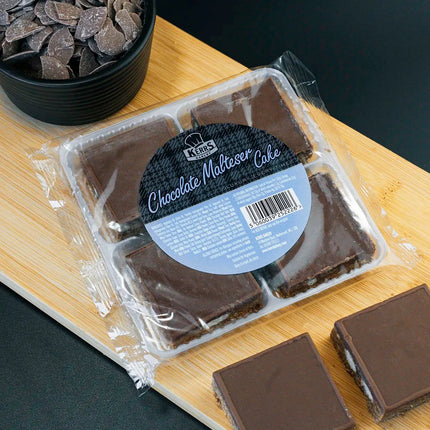 Packaged chocolate malted cake on a wooden board with loose pieces beside it.