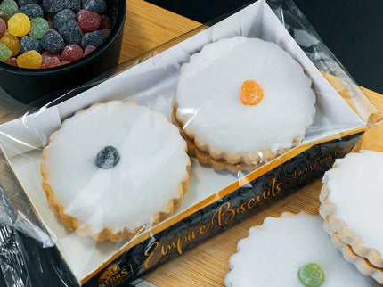 Box of white cookies with colorful centers on a wooden board