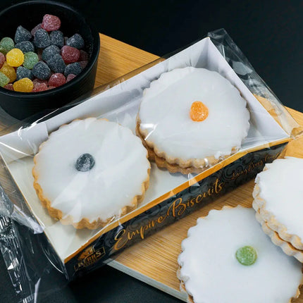 Box of white cookies with colorful centers on a wooden board