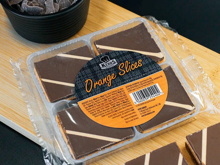 Packaged chocolate orange slices on a wooden board with a black background