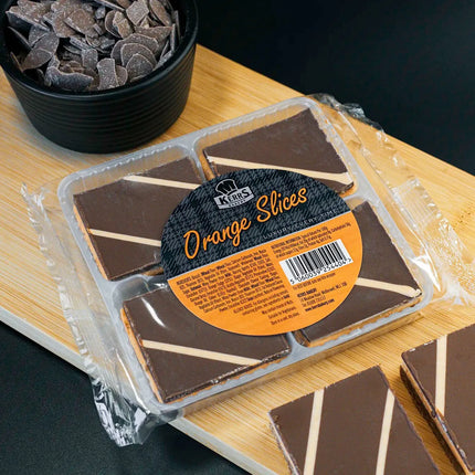 Packaged chocolate orange slices on a wooden board with a black background